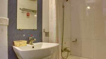Un baño con lavamanos blanco, espejo, ducha y toallero.