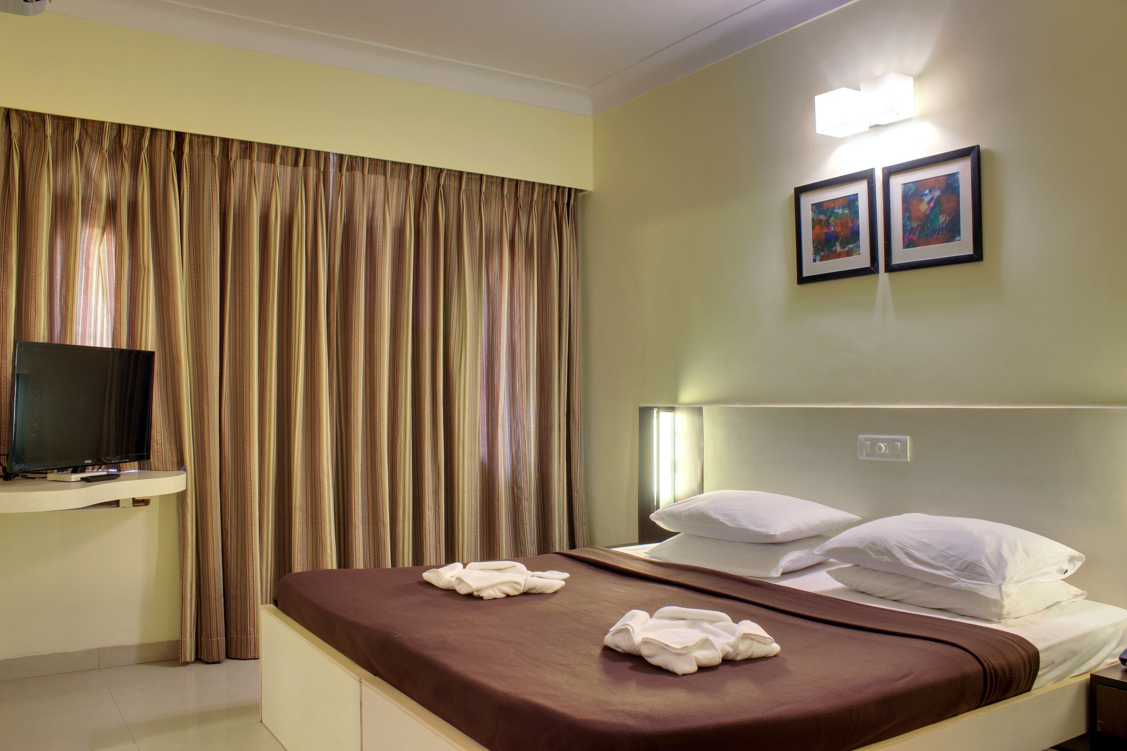 Una habitación de hotel con cama, televisor y cortinas.