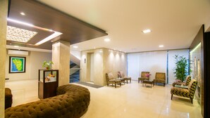 Een moderne lobby met een gebogen bank, meerdere fauteuils, een trap en een grote potplant.