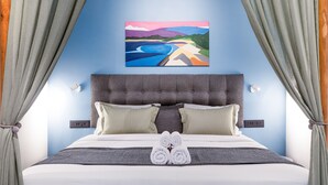 Een net opgemaakt bed met hoofdbord, kussens en opgerolde handdoeken.