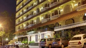 Een meerlaags hotel met balkons, een parkeerplaats en een restaurant.