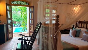 A bedroom with a bed, a rocking chair, and a view of a swimming pool. - Nooit Gedacht Heritage Hotel-Original Dutch Governor's House (Unawatuna)