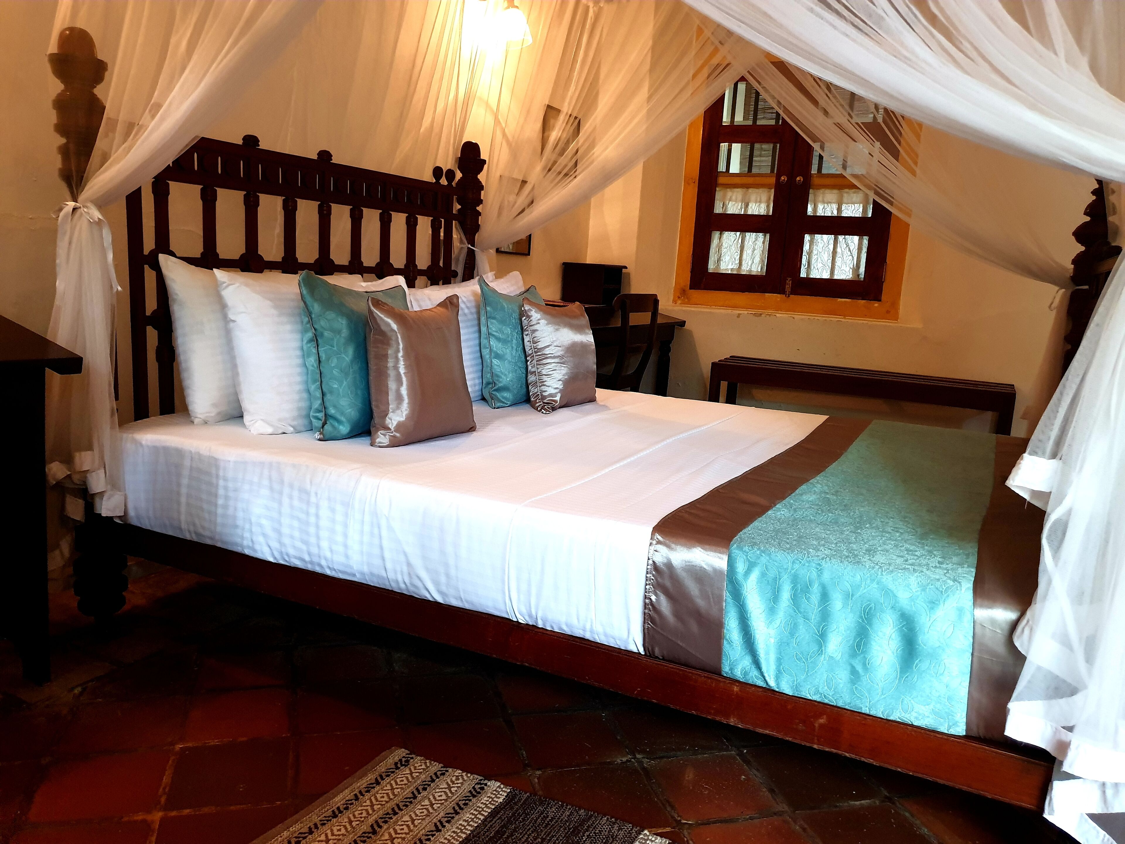 Una cama con dosel, cabecera de madera y varias almohadas.