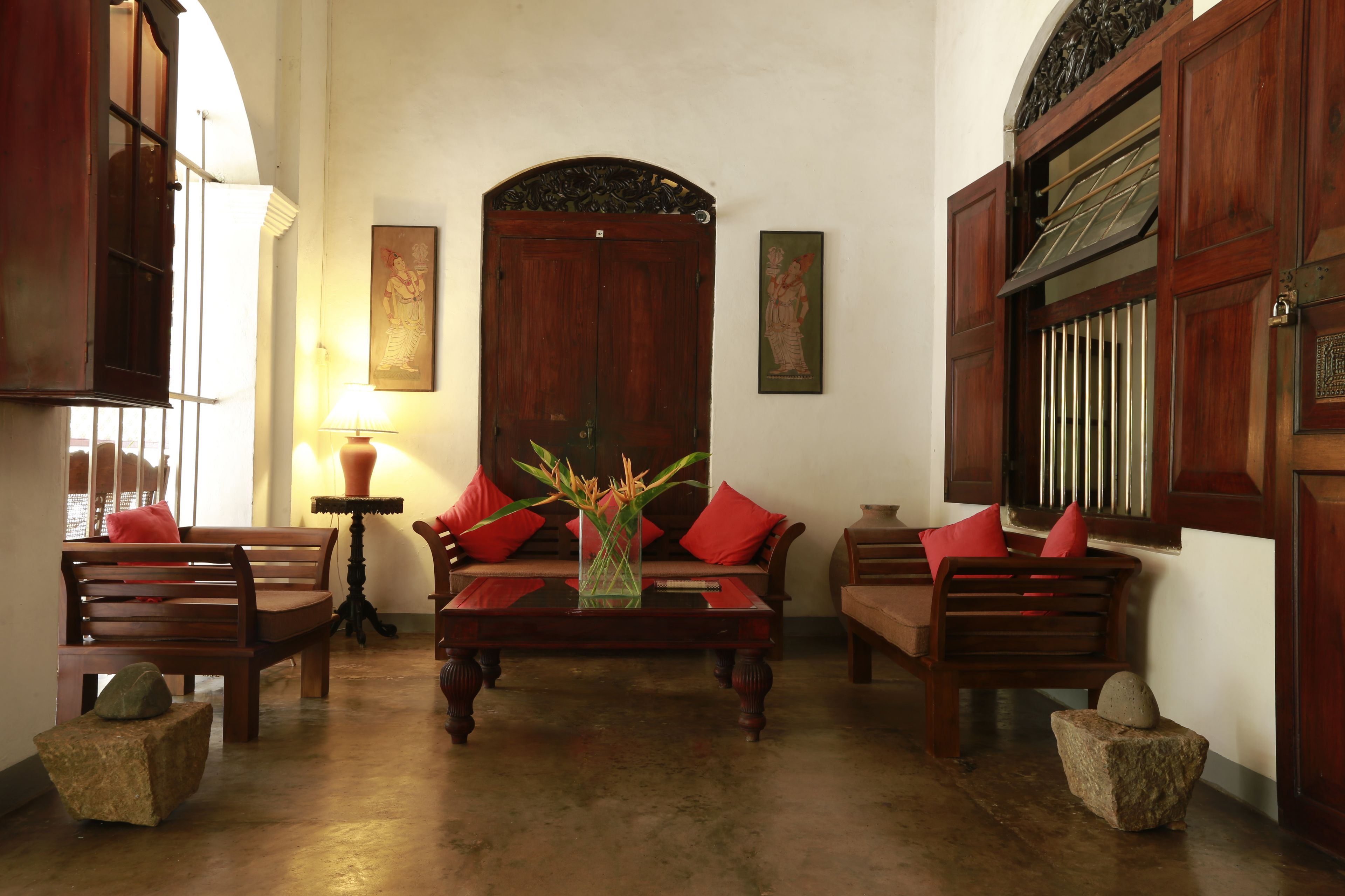 Una habitación tradicional con muebles de madera, un sofá central y un jarrón decorativo.