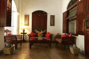 Una habitación tradicional con muebles de madera, un sofá central y un jarrón decorativo.
