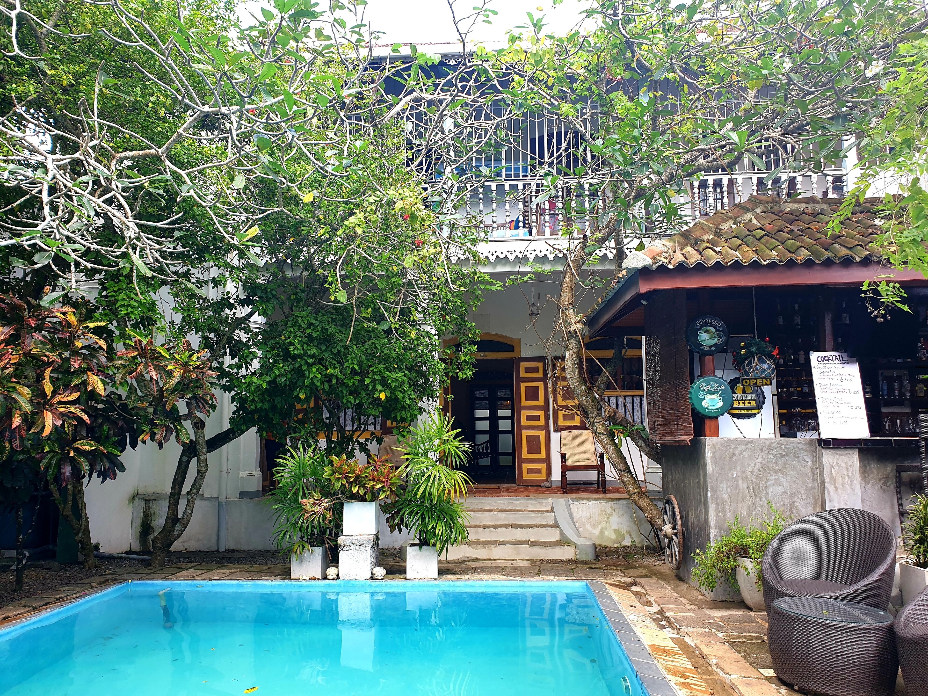 A pool area with a clear view of a bar and a staircase leading to a balcony.