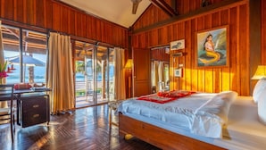 Una habitación de madera con una cama, un escritorio y vistas al mar.
