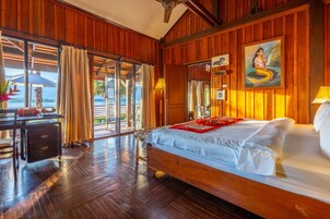 Una habitación de madera con una cama, un escritorio y vistas al mar.