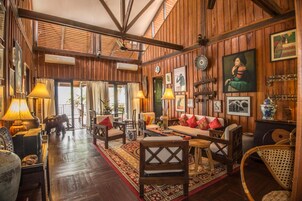Una habitación amplia con paredes de madera, un gran conjunto de sofás y una zona de comedor con sillas y una mesa.