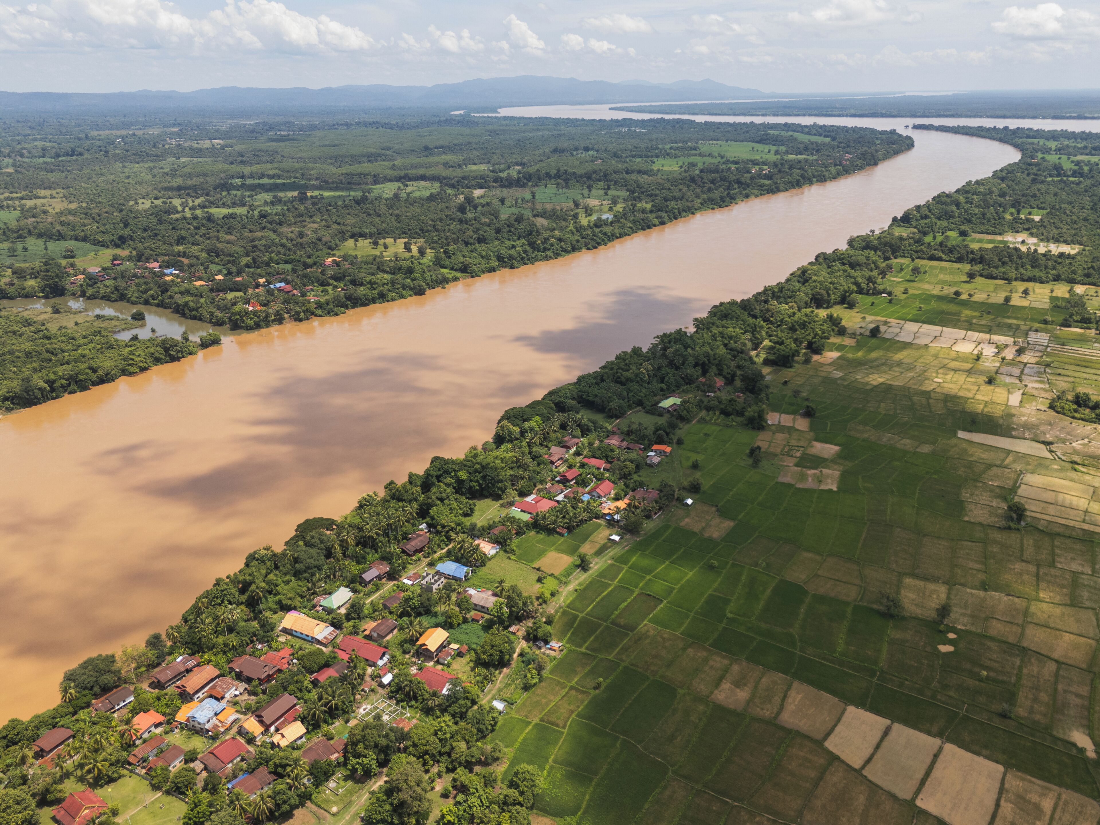 Vista aerea di un fiume che scorre attraverso una zona rurale con case e campi.