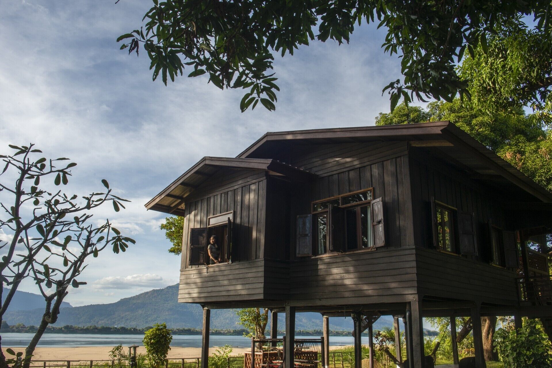 Une maison en bois dotée d’un balcon, située au bord d’un lac, avec des montagnes en toile de fond.