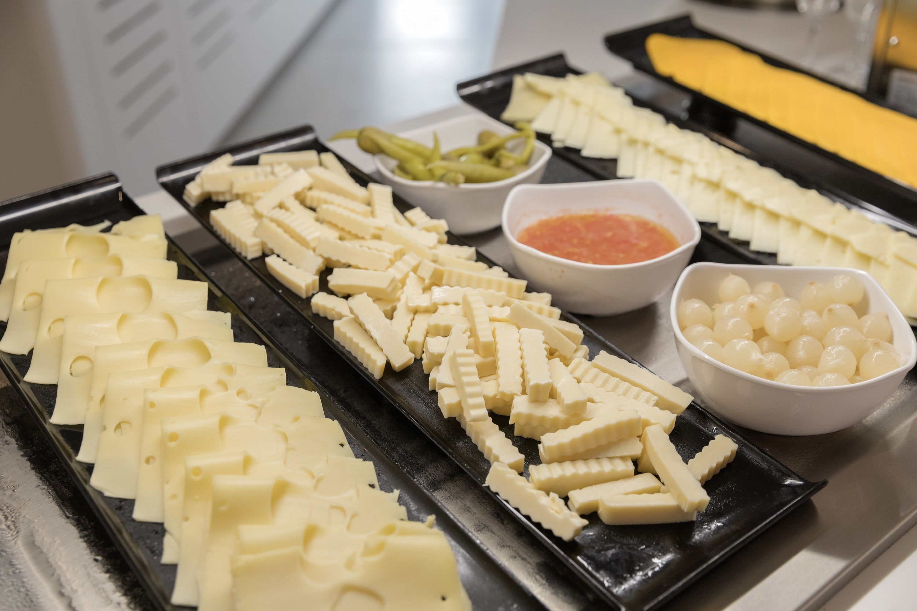 A buffet with various cheeses and dips.