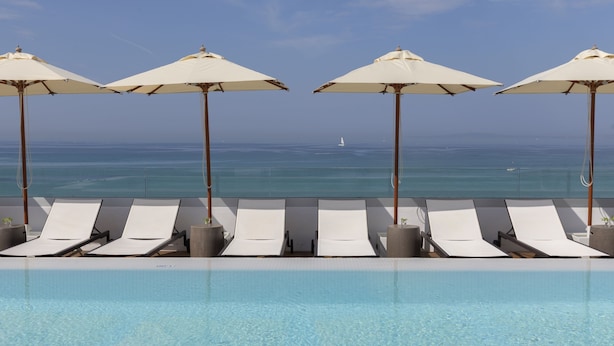 A poolside area with lounge chairs and umbrellas, overlooking the ocean. - Hotel HM Ayron Park – Adults Only (Palma de Mallorca)