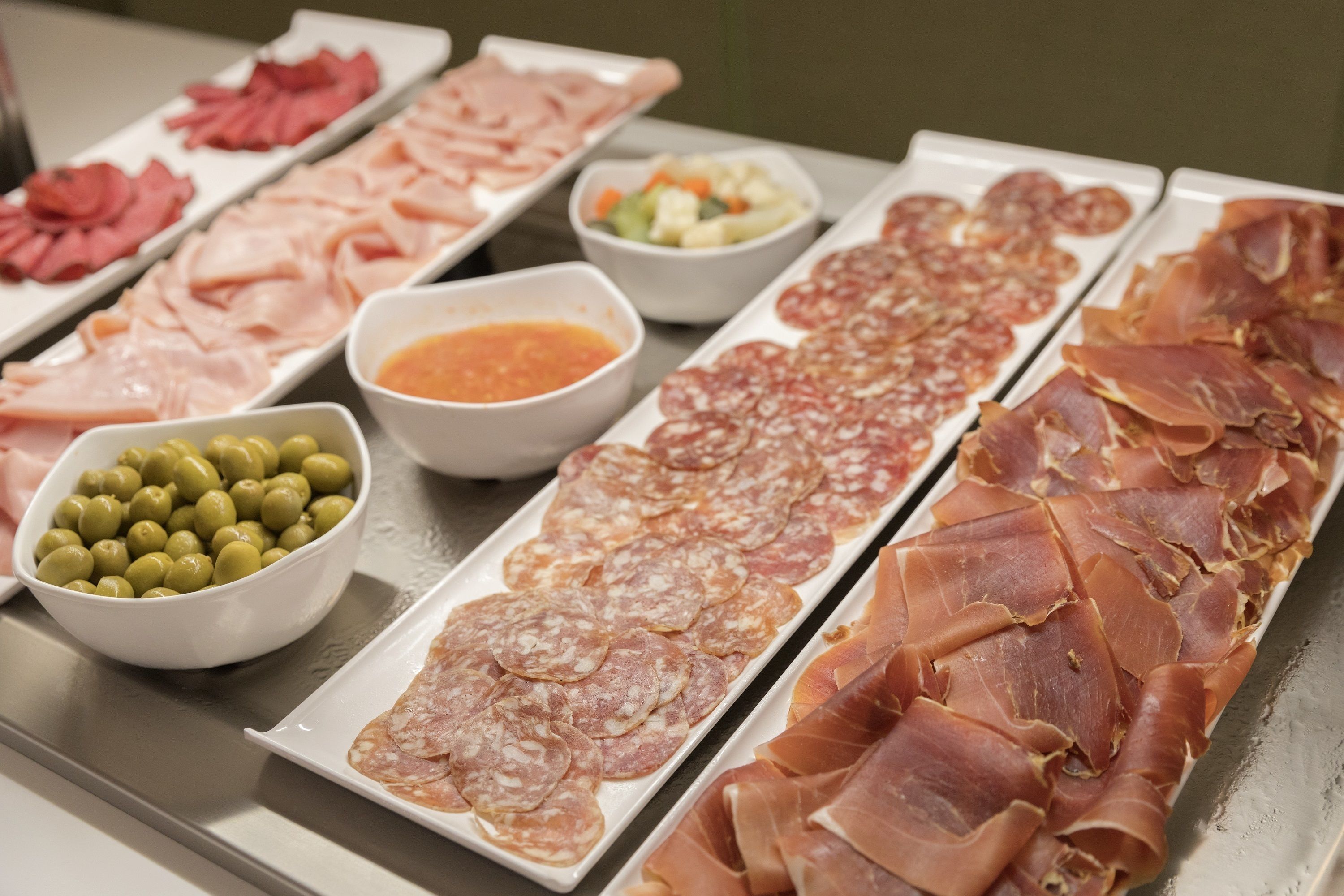 Un buffet proposant différentes sortes de viandes et d’olives.