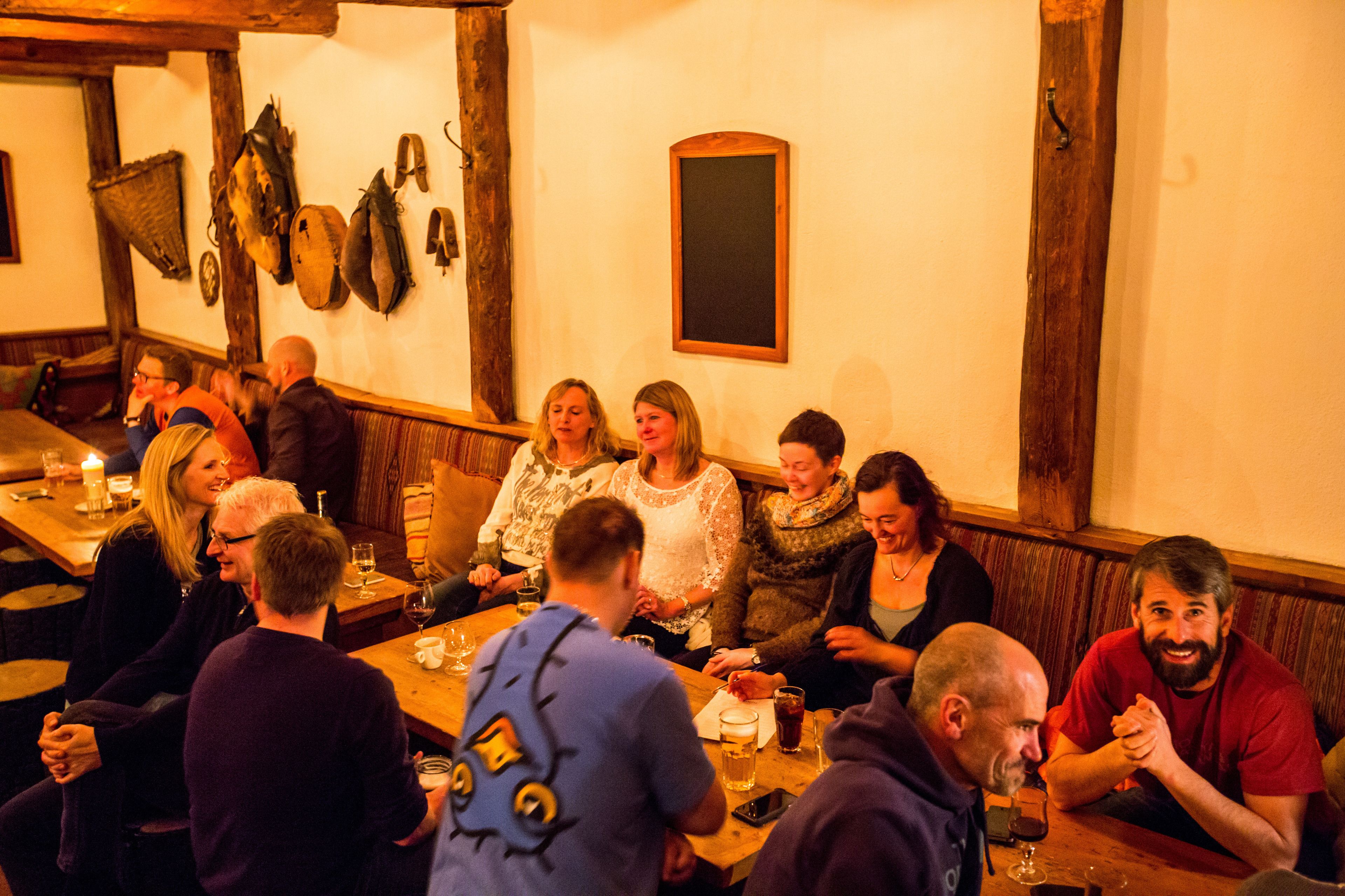 A group of people seated around a wooden table in a rustic setting with exposed beams and traditional decor.