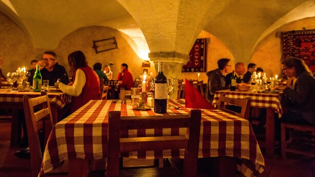 A dimly lit restaurant with checkered tablecloths and candle-lit tables. - Langley Hotel La Vieille Ferme (La Salle-les-Alpes)