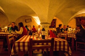 Un restaurante con poca luz, manteles a cuadros y mesas iluminadas con velas.