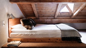 A cozy attic bedroom with a wooden ceiling, a single bed, a small bedside table with a lamp, and a window letting in natural light. - Langley Hotel La Vieille Ferme (La Salle-les-Alpes)