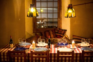 A dining table set with plates, glasses, and candles, with a bottle of wine and a candle on the table. - Langley Hotel La Vieille Ferme (La Salle-les-Alpes)