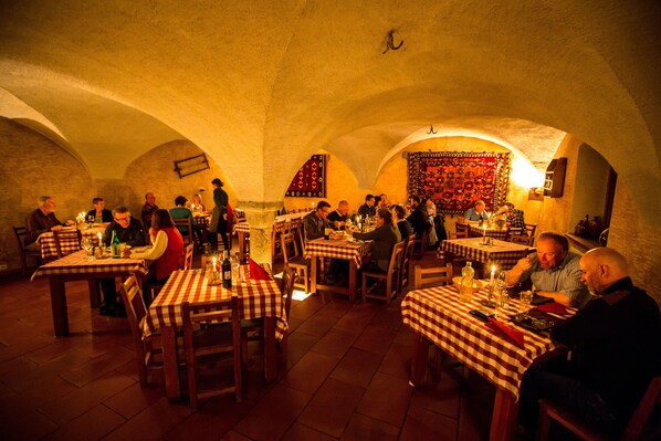 A restaurant with checkered tablecloths, wooden chairs, and a warm, dimly lit ambiance.