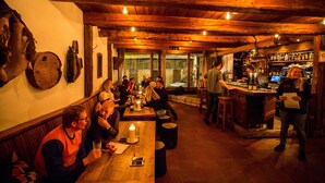 A rustic interior with wooden beams, a bar area, and a seating arrangement for guests. - Langley Hotel La Vieille Ferme (La Salle-les-Alpes)