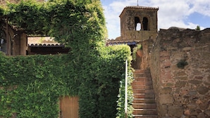 A stone staircase leading to a tower, surrounded by greenery and a stone wall. - Encís d Empordà (Corca)
