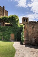 A stone staircase leading to a tower, surrounded by greenery and a stone wall.