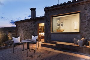 Un edificio de piedra con un amplio ventanal, mesas al aire libre y una chimenea.