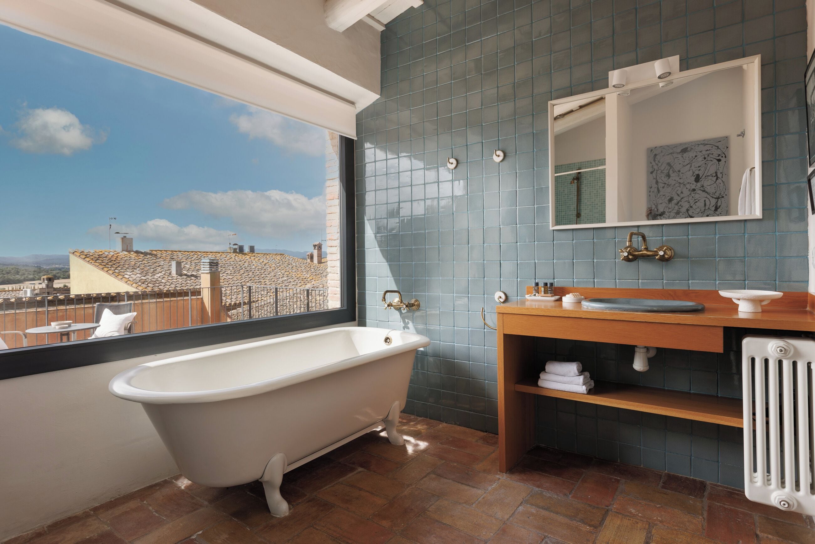 A bathroom with a freestanding bathtub, a wooden vanity, a mirror, and a view of the cityscape.