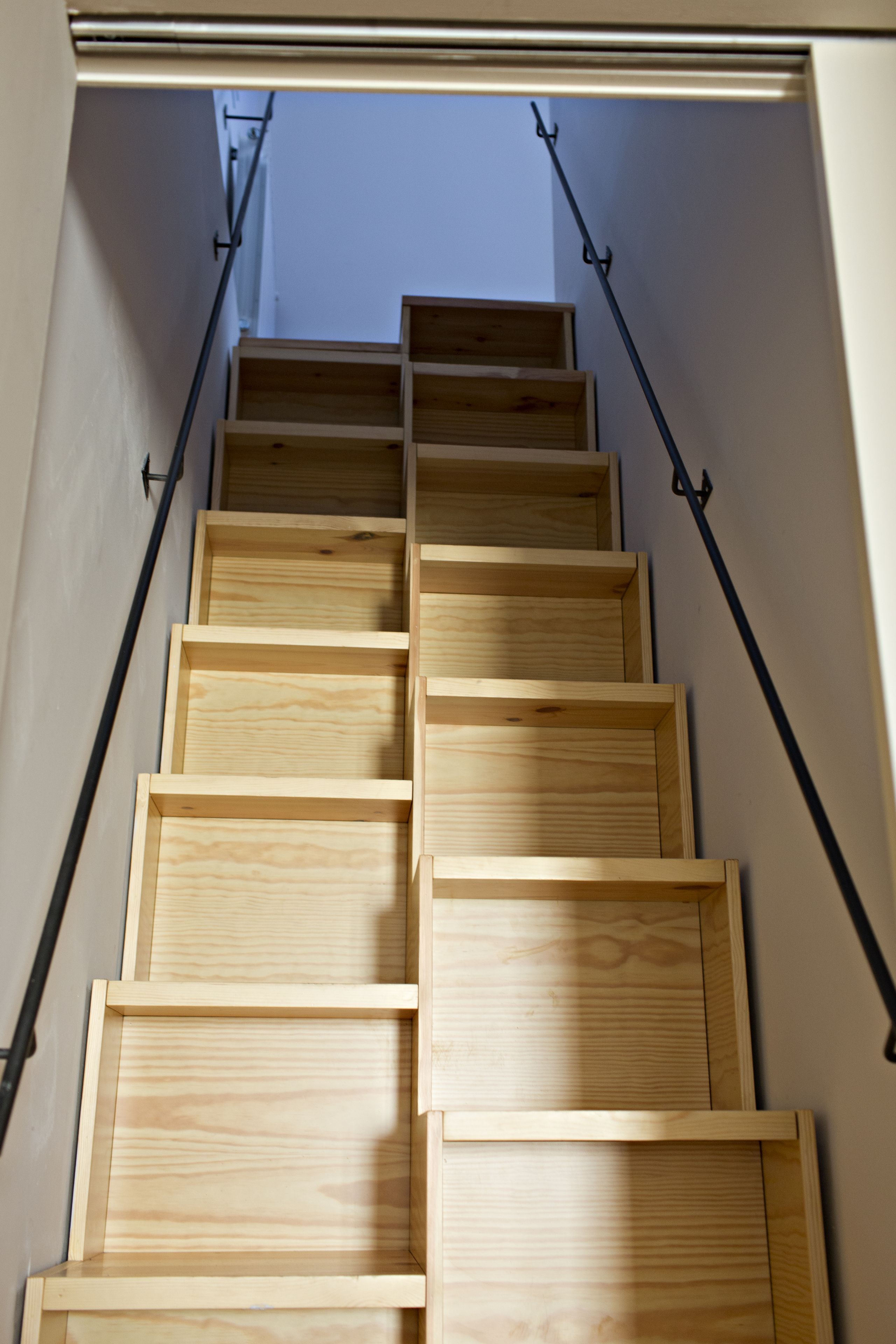 Una escalera de madera con barandillas de metal que sube a un nivel superior.