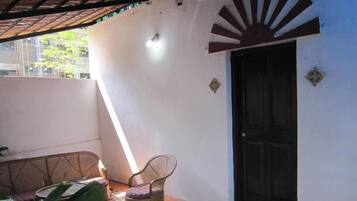 Una habitación con una sola silla, una puerta y una pared decorada con un motivo de sol.