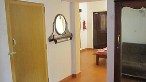 A hallway with a wooden door, a mirror, and a dark-colored sofa in the background. - Hotel Vivenda Rebelo (Panaji)