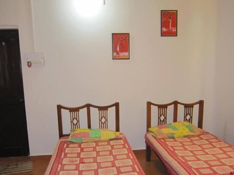 Une chambre avec deux lits simples, une porte et deux tableaux encadrés au mur.