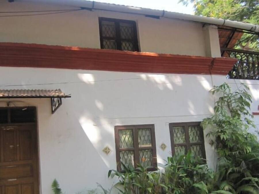A two-story building with a white facade, a wooden door, and windows with metal grilles.