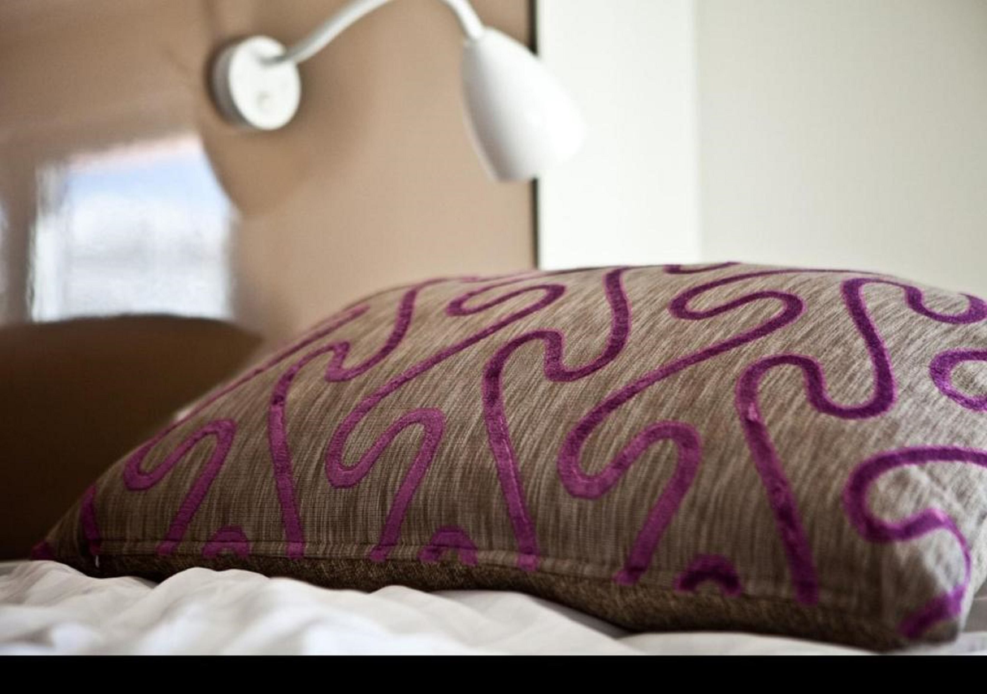 A pillow with a geometric pattern on a bed.