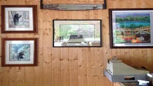 A room with wooden walls, framed pictures, a window, and a small desk with a telephone.