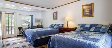 A hotel room with two beds, a desk with a chair, a lamp, and a window with curtains.