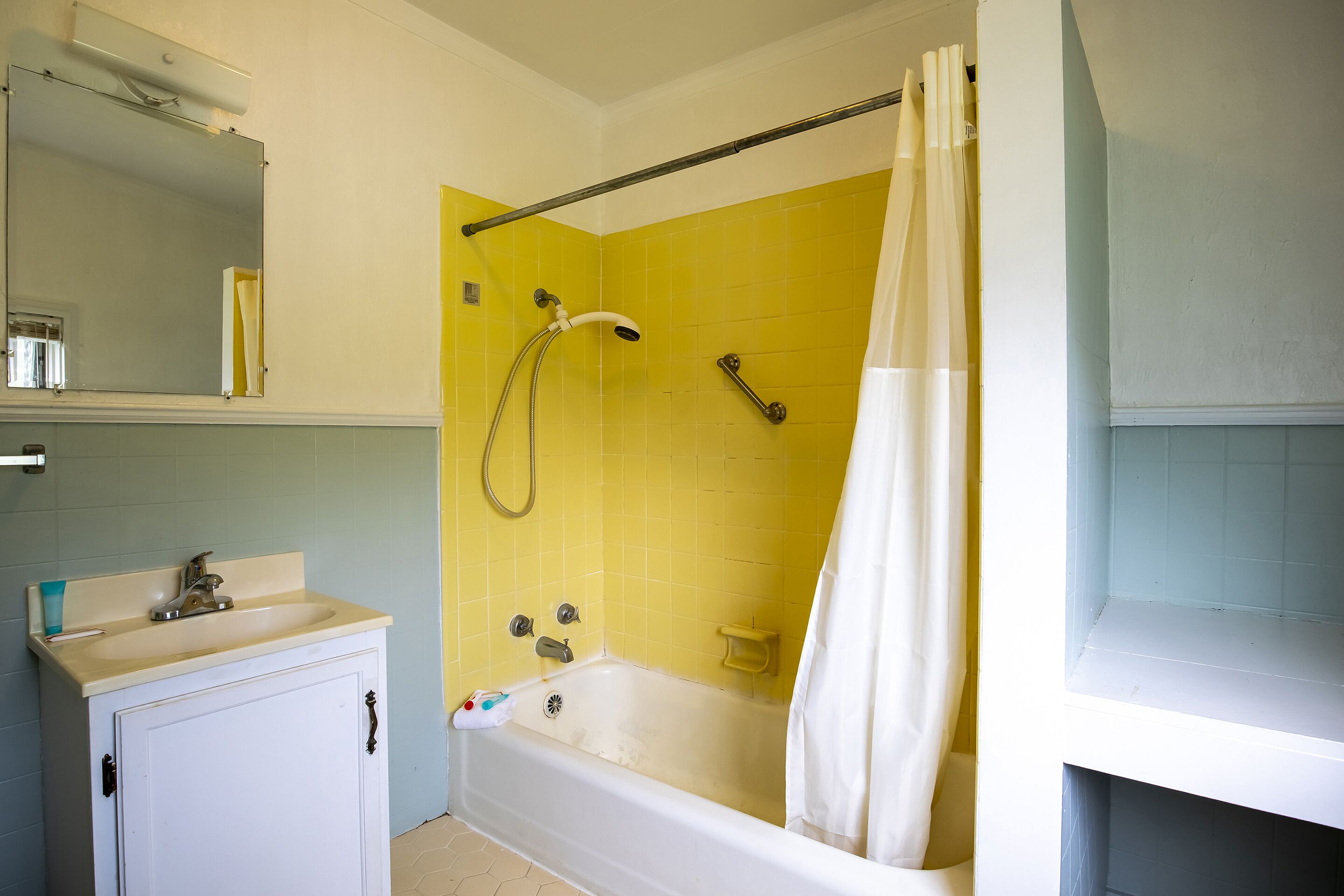 A bathroom with a bathtub, a sink, and a mirror.