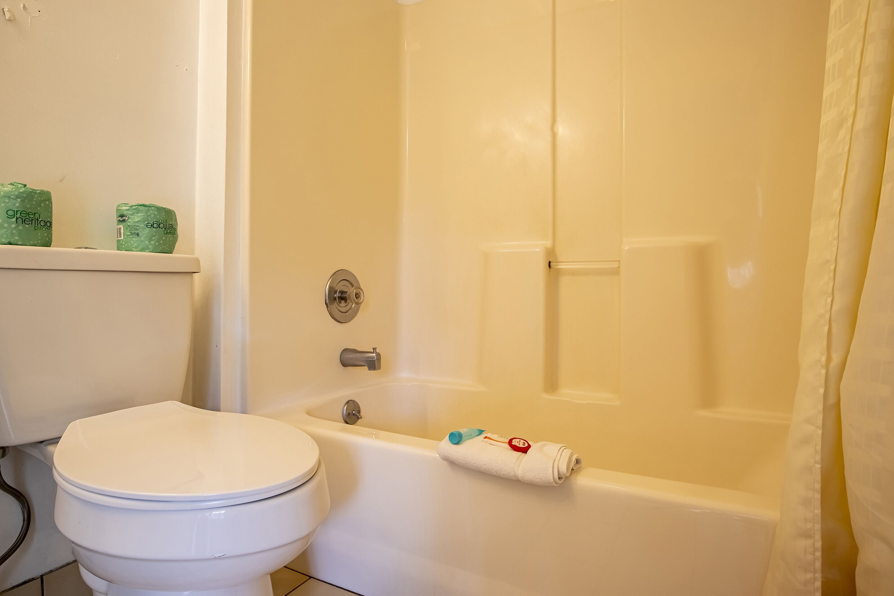 A bathroom with a toilet, a bathtub, and a shower curtain.