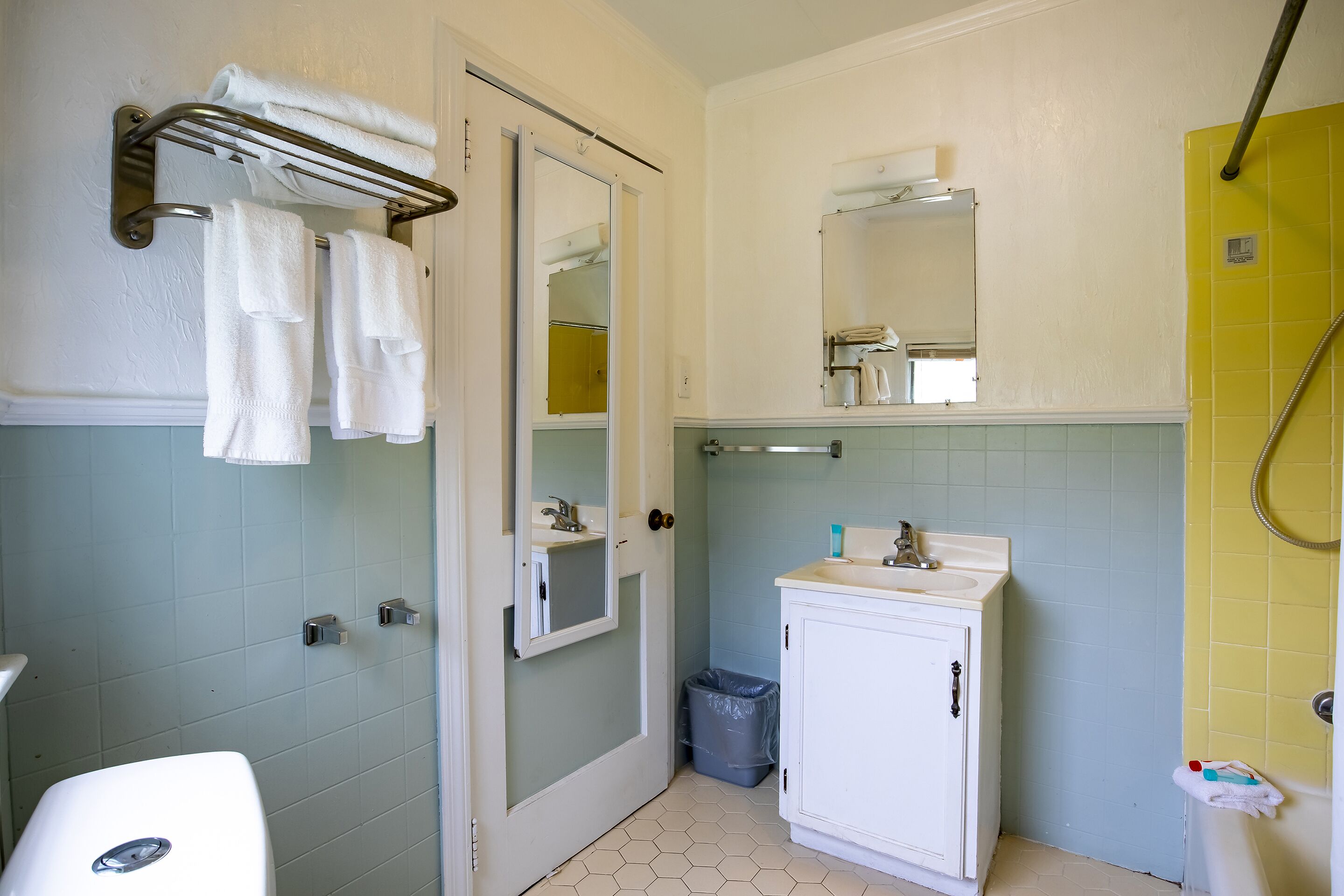 A bathroom with a white sink, a mirror, a towel rack, and a shower area.