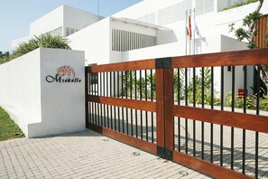A modern building with a white facade, a wooden gate with black metal bars, and a logo on the wall. - Michelle Boutique Hotel (Balapitiya)