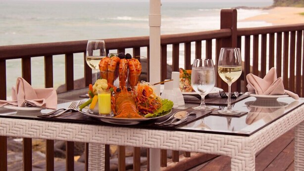 Una mesa de comedor con mariscos, copas de vino y vista al océano.