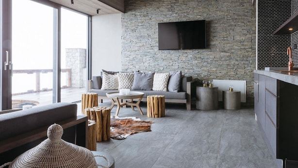Uma sala de estar moderna com parede de pedra, TV de tela plana, sofá e mesa de centro.