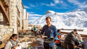 Restaurante com mesas ao ar livre, com vista para uma montanha coberta de neve.