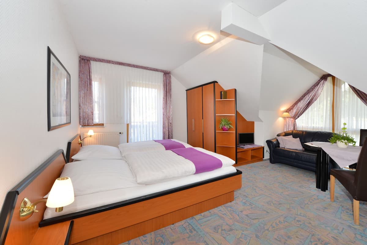 Un dormitorio con cama, escritorio, sofá y armario.