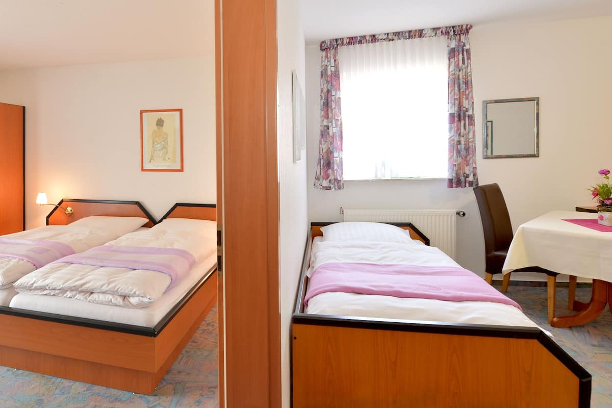 Un dormitorio con cama, armario y ventana con cortinas.