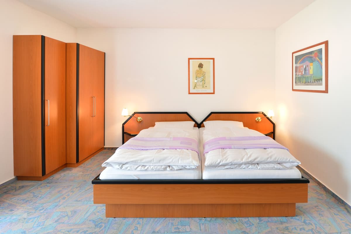Un dormitorio con una cama de madera, dos mesitas de noche, un armario y dos lámparas de pared.
