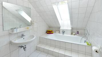 A modern bathroom with a freestanding bathtub, a sink, and a large mirror.