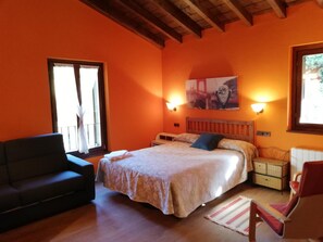 A bedroom with a bed, a sofa, a chair, and a window.