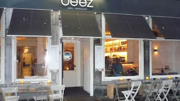 Un área de estar al aire libre con mesas y sillas frente a un edificio con un letrero que dice 'beez'.